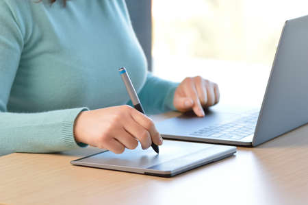 Close up of woman designer working drawing with a digital pen at homeの写真素材