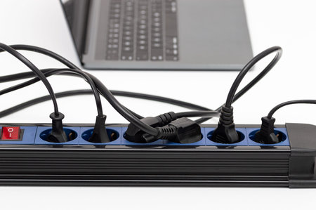Close up of a plug in an electrical socket on a table at home with many connections and electrical...