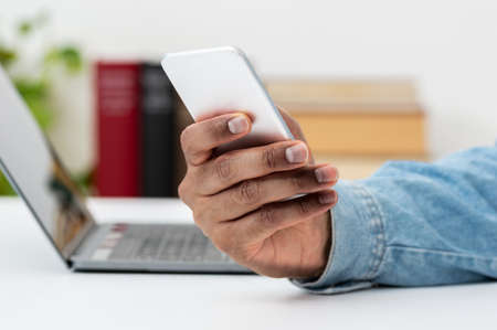 Cropped shot of a businessman using a mobile phone and laptop at his work deskの写真素材