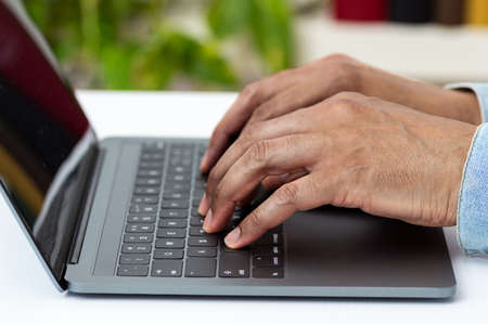 Closeup shot of an unrecognizable man working on a laptop at homeの写真素材