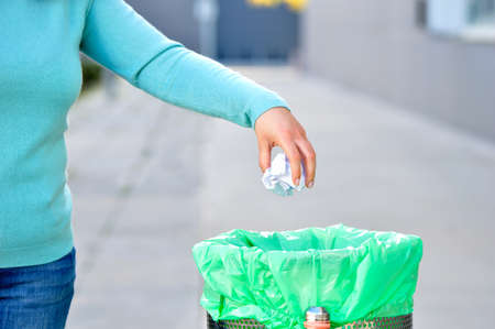 Civic woman throwing garbage in a trash bin a cityの写真素材