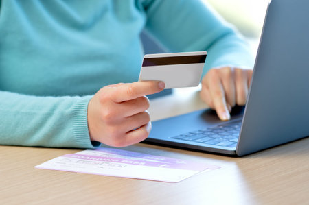 Cropped shot of a woman hands paying boarding pass with credit card at home