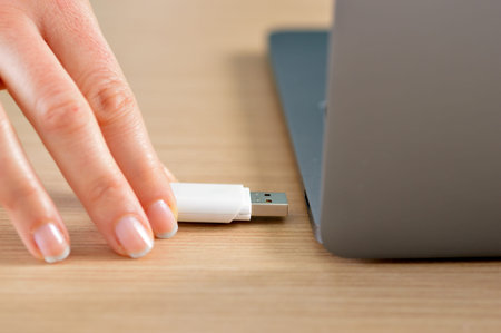 Close up of a woman hand connecting a pendrive in a laptop on a desktop