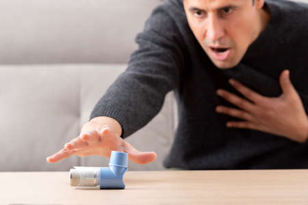 Man suffering asthma attack reaching inhalerの写真素材