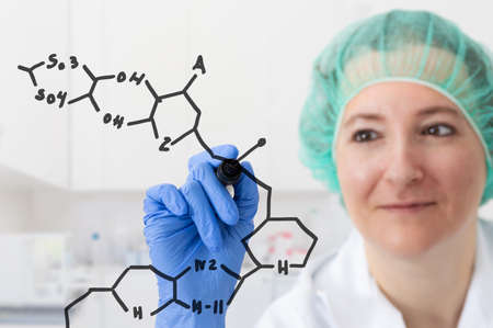 Shot of a focused young female scientist solving equations on a glass wall in a laboratoryの写真素材