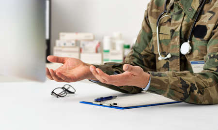 Cropped shot of a army doctor speaking video conferencing on computer using online video call consultation app.の写真素材