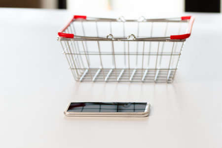 Laptop, empty shopping basket metal on table at home. Internet shopping conceptの写真素材