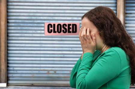 Close-up view of a woman covering her face and crying with Business office or store shop is closed, in concept of economic crisis and copy spaceの写真素材
