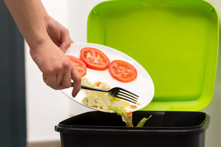 Close-up of a person throwing a half-finished banana with vegetables into the bin.Concept of food...