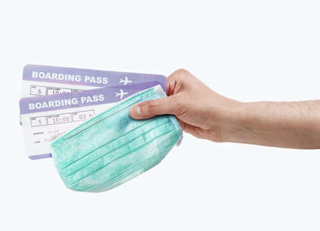 Cropped shot of a man holding his passport, mask and boarding pass with white background.の写真素材