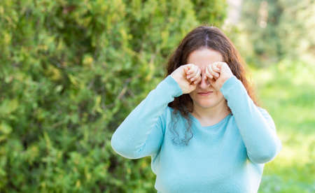 Woman suffering itching scratching eyes in a parkの写真素材