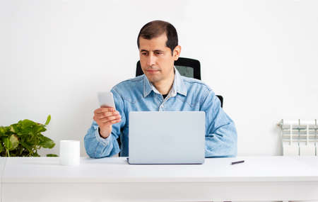 Cropped shot of a young businessman standing alone in his home office and texting on his cellphoneの写真素材