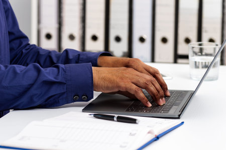 Closeup shot of an unrecognizable man using a laptop while working from office