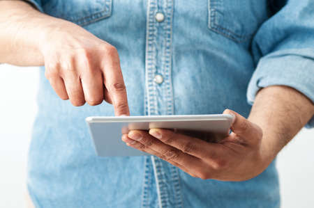 Cropped shot of an unrecognizable businessman standing alone in his home office and surfing on his digital tabletの写真素材