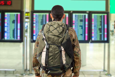 Shot of a soldier checking the flight times in an airportの写真素材