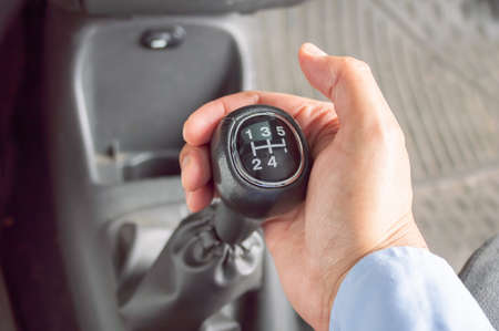 Cropped shot of a businessman changing the gears of a car.Hand holding manual gearbox in car.の写真素材
