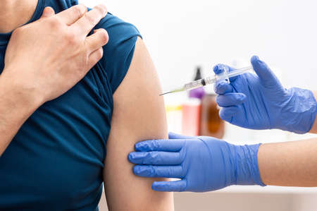 Shot of a nurse applying a bandaid to his patien's arm against covid 19の写真素材