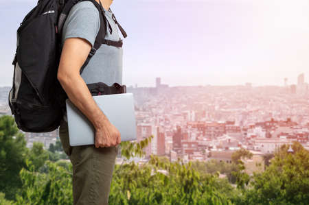 Unrecognizable digital nomad man traveling the world working with his laptop with a background cityの写真素材