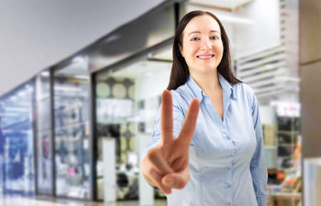 woman making the victory sign in a shopping mallの写真素材