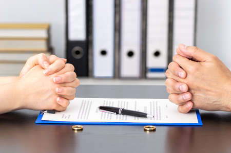Hands of wife and husband signing divorce documents or premarital agreement at the lawyer's officeの写真素材