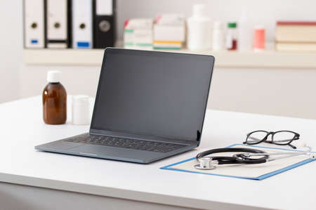 Cropped shot of technology and a notebook on a desk in an empty hospital office during the dayの写真素材