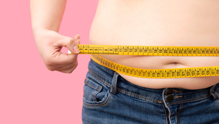 Close up of fat girl with overweight checking out his weight isolated on white backgroundの写真素材