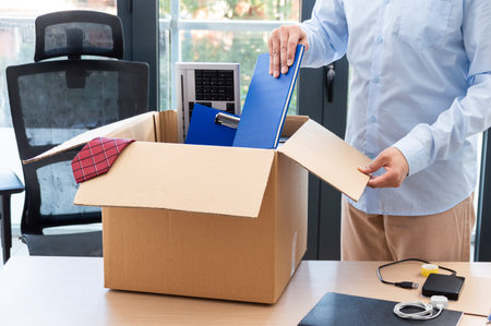 Cropped shot of a businessman leaving work putting his belongings in a box with his objects at...