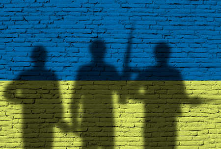 Flag of Ukraine painted on a brick wall with soldiers. War between Ukraine and Russiaの写真素材