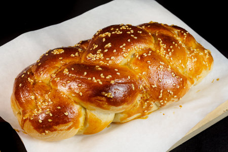 challah Jewish bread on white paper and  black background. clouse-up