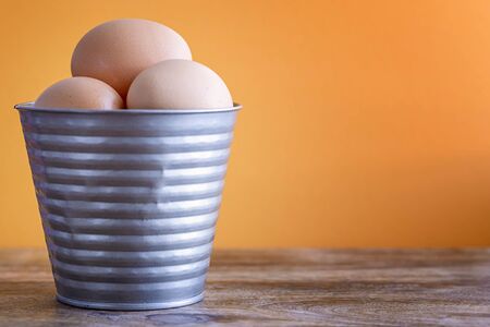 eggs in tin bucket orange background on woodの写真素材