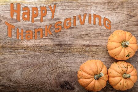 three small pumpkin with happy thanksgiving written on woodの写真素材