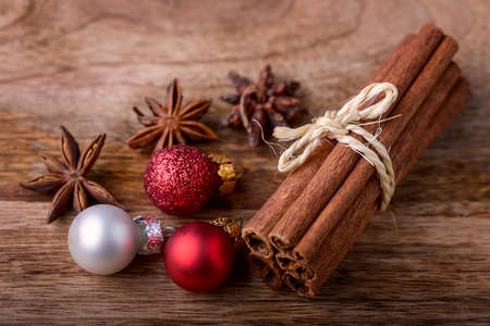 cinnamon and star anise with red and white christmas balls on woodの写真素材