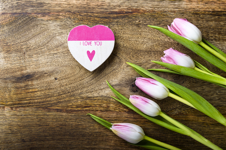 five pink tulips and wooden heart with i love you written on wooden backgroundの写真素材
