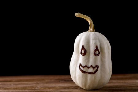 small decorative pumpkin isolated on wood with chocolate faceの写真素材