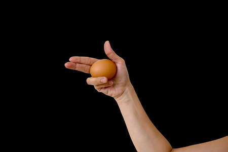 gun hand sign with egg on black backgroundの写真素材