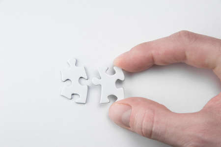 A Hand bringing two puzzle pieces togetherの写真素材