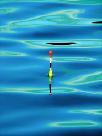 Photo of a float during fishing on lake at small excitement of water.の写真素材