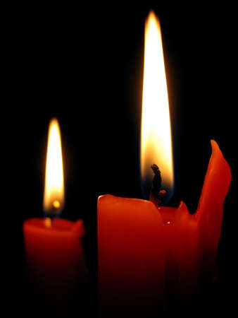 Two red burning candles on a black background.の写真素材
