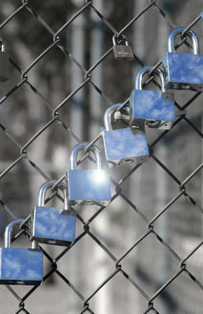 locks in a row with clouds reflections hanging on a fenceの写真素材