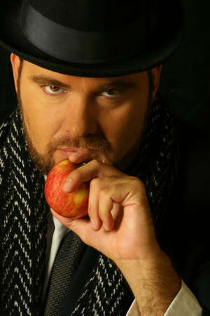 sinister bearded man holding an apple in front of his mouthの写真素材