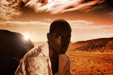 Portrait of good looking young African-American male against dunes with dramatic sky in red tonesの写真素材