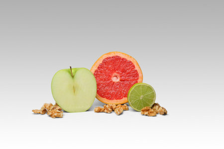 Still life composition of sliced fruit and nuts on white backgroundの写真素材