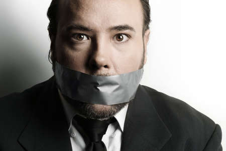 Dramatic stylized close-up of a very businessman with duct tape covering his mouthの写真素材