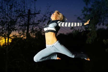 Cool dancer woman jumping through the air in stylish athletic wardrobeaの写真素材