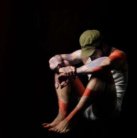 Fine art full body portrait of a soldier in American flag body paint and green army hat against black backgroundの写真素材