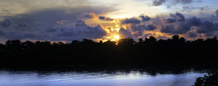 a beautiful island morning sunrise with a sky full of tropical clouds and reflective water in...