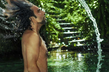 Man with long hair playing in waterの写真素材
