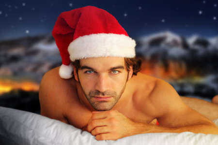 Sensual portrait of a young shirtless male model laying on pillow against fantasy winter backgroundの写真素材