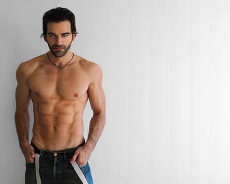 Body portrait of a sexy young man in jeans against neutral backgroundの写真素材