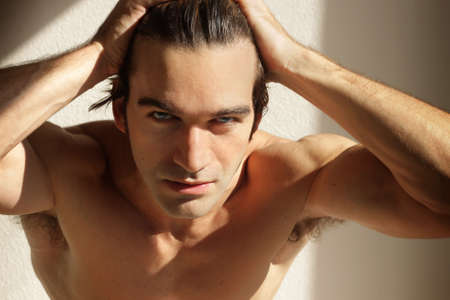 Dynamic portrait of a sexy shirtless man with hands on his headの写真素材